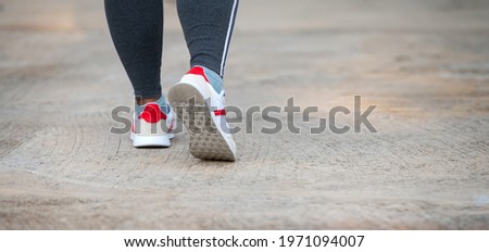 Running sport.Chubby woman runner legs and shoes in action on road.Photo select focus.