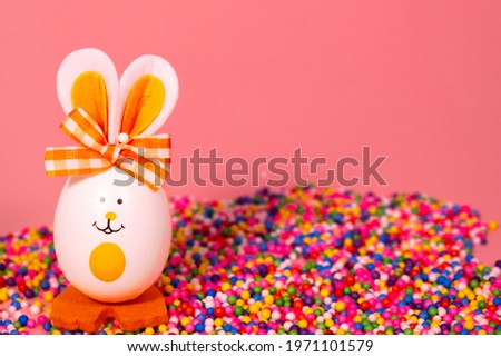 Ideas for holiday decoration. Easter eggs looking like a rabbit. With a painted face. On a light pink background. Copy space. Isolated.