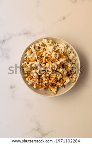 A bowl full of pop corn on a white background