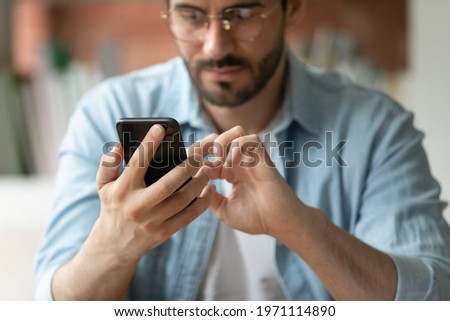 Close up cropped of confident businessman in glasses using smartphone, typing and looking at screen, checking email, reading news, chatting online in social networks or searching information Royalty-Free Stock Photo #1971114890