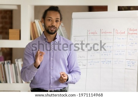 Head shot portrait African American man teacher recording webinar, explaining, speaking and looking at camera, mentor coach leading online lesson, making flip chart presentation, remote education Royalty-Free Stock Photo #1971114968