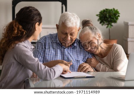Reaching an agreement. Happy old spouses visiting lawyer broker realtor to buy real estate sign insurance policy create will. Excited aged married couple clients sign financial deal with bank manager Royalty-Free Stock Photo #1971114989