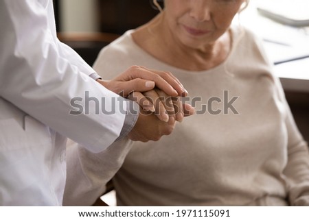 Mental support. Close up of disabled sick senior female hand in palms of young woman in white medical uniform. Attending physician nurse comforting taking care of unhealthy aged lady geriatric patient Royalty-Free Stock Photo #1971115091