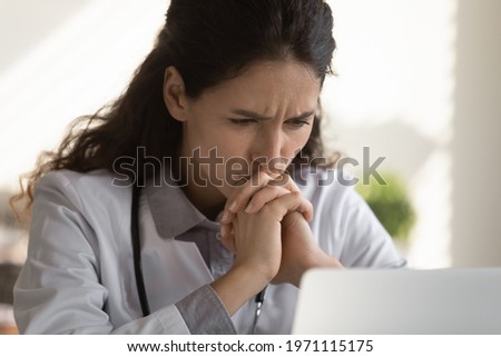 Difficult case. Thoughtful female doctor look at office computer screen ponder on establishing correct diagnosis choose treatment. Hard thinking medic study medical file of patient with rare disease Royalty-Free Stock Photo #1971115175