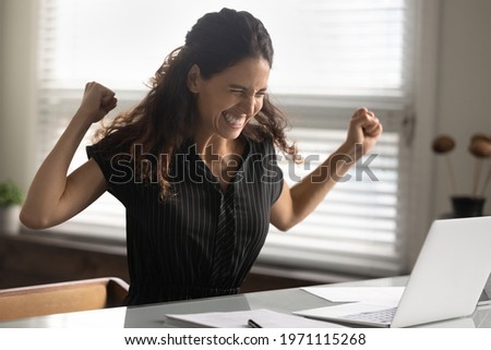 Getting promotion. Joyful young latin woman office worker yell look on pc screen receive recognition reward for good job from boss. Female scientist feel excited to find solution of difficult problem Royalty-Free Stock Photo #1971115268