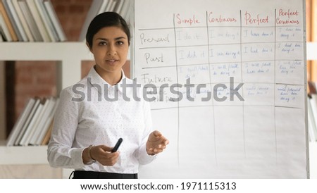 Head shot portrait Indian woman teacher making flip chart presentation, recording webinar, speaking and looking at camera, mentor coach leading online lesson, teaching and explaining, e-learning