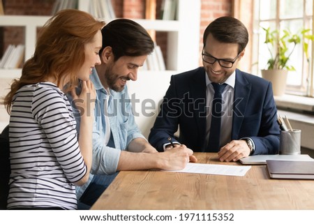 Happy millennial couple signing contract with manager at meeting, excited satisfied clients purchasing first own apartment, making insurance or investment deal, putting signature on document