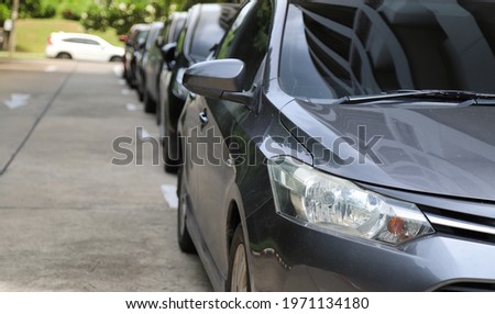 Closeup of front side of gray car with  other cars parking in outdoor parking area beside the street with natural background.