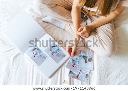 Top view of Cropped woman hands holding and watching a family photo album. Mother sit on bed and watching album with little baby son kid boy. Royalty-Free Stock Photo #1971143966