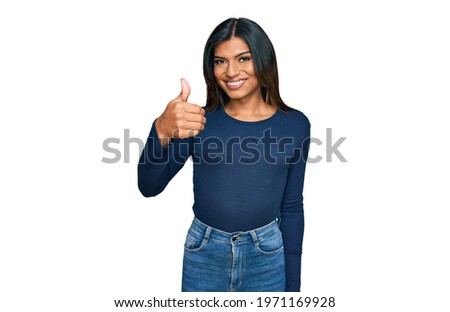 Young latin transsexual transgender woman wearing casual clothes smiling happy and positive, thumb up doing excellent and approval sign 