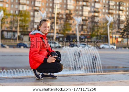 A young girl photographs nature in the park with a SLR camera.