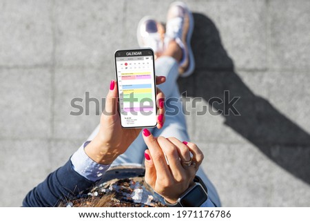 Woman using calendar app on her phone Royalty-Free Stock Photo #1971176786