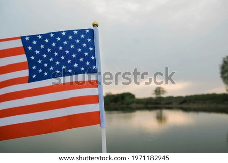 Miniature flag of American is isolated ackground of a beautiful landscape in summer. Politics, learning a foreign language. 4 July. Memorial Day.
