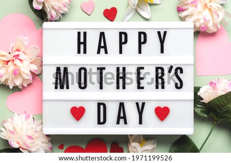 Happy Mother's Day.Lightbox with the word Happy Mother's Day next to hearts and flowers on a green background