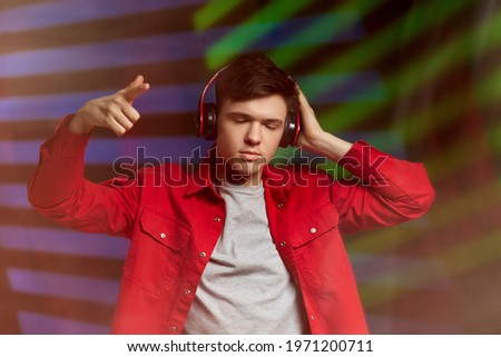 young man in red shirt with headphones listening to music
