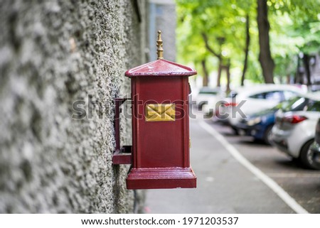 Metal mailbox painted in red color attached to a wall on an urban street