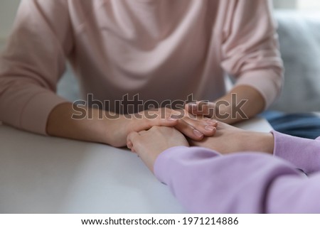 Close up young loving mother holding hands of teen kid daughter, giving advice against school bullying or showing psychological support and care, having sincere trustful conversation at home. Royalty-Free Stock Photo #1971214886
