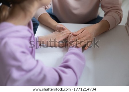 Close up young adolescent child girl holding hands of caring mommy, sharing life problems in sincere trustful conversation. Loving mother giving psychological support to stressed teenage daughter. Royalty-Free Stock Photo #1971214934