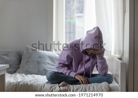 Unhappy young adolescent 12s kid girl sitting on comfortable bed, feeling exhausted or depressed alone at home. Stressed teen child suffering from headache or having psychological mental problems. Royalty-Free Stock Photo #1971214970