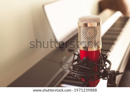 Red condenser microphone at home studio for voice recording.
