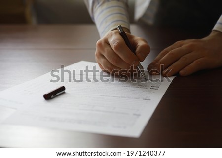 Business meeting. A man signs a contract. Male hand with pen makes notes in office.