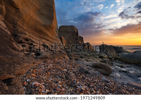 Russia. Dagestan. Dawn on the seashell-strewn rocky shore of the Caspian Sea near the city embankment of Makhachkala. Royalty-Free Stock Photo #1971249809