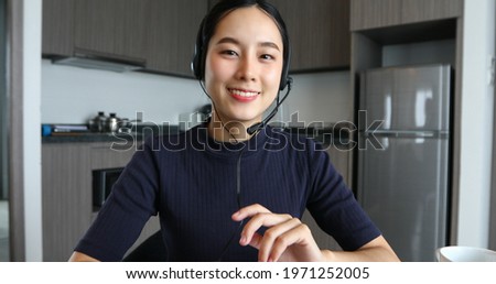 Asian women wearing headphone and using digital tablet video Conference and meeting and drinking coffee in The kitchen at the home