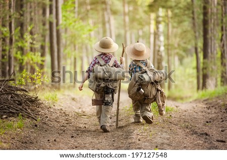 Two boys go hiking with backpacks on a forest road bright sunny day Royalty-Free Stock Photo #197127548