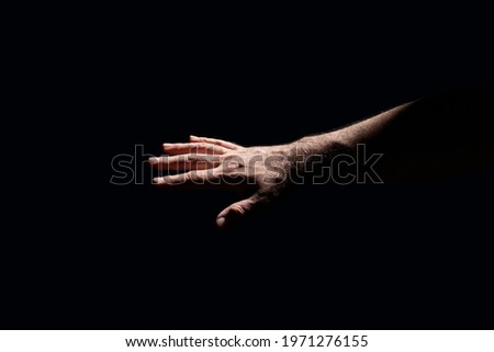 Light shining on a male hand in total darkness 