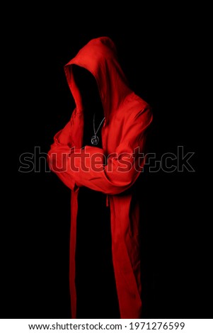 Mystery man in a red hooded cloak in the dark. Unrecognizable person. Hiding face in shadow.Ghostly figure. Sectarian. Conspiracy concept. Royalty-Free Stock Photo #1971276599