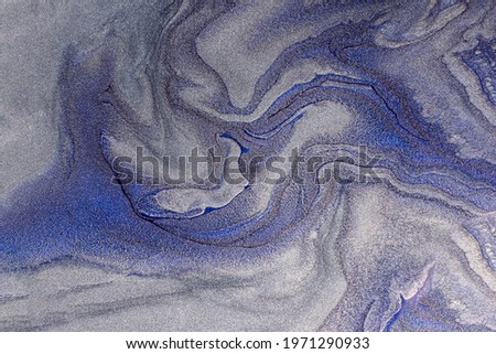 Beautiful shimmer blue and silver stains of liquid nail polish with bubbly texture.Stripy paint texture.Nail lacquer flow modern backdrop. Minimalism concept.Copy space.