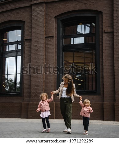 young beautiful mother with long hair with children on walk in street happiness joy fun motherhood