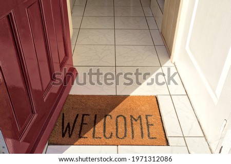 Open front door of house with Welcome door mat entering in the Hallway of a modern new home sunlight