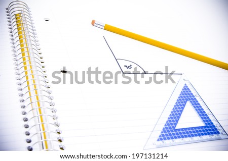 A pencil and geometry tool laying on an open notebook.