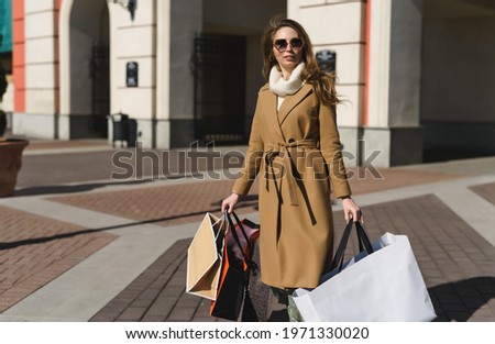 Successful shopping! A young attractive European woman holding in her hands a lot of shopping packages from various clothing and footwear stores.