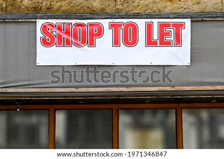 Large banner on the outside of a business which has closed down advertising a shop to let. No people.