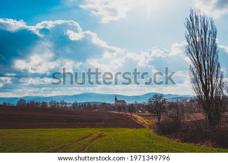 view of fields and hills with the village and mountains in the background