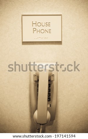 A phone on the wall with a sign above that says house phone.