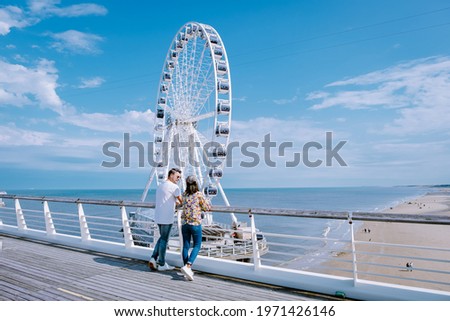  The Ferris Wheel The Pier at Scheveningen, The Hague, The Netherlands on a Spring day, couple man and woman mid age on the beach Royalty-Free Stock Photo #1971426146