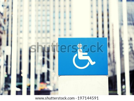 A disabled sign on a blue cube which is on top of a white cube.