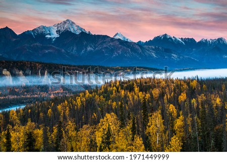 dramatic autumn  sunrise in the Chugach mountain range surrounded by colorful autumn foliage in Alaska. Royalty-Free Stock Photo #1971449999