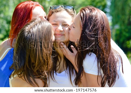 4 beautiful friends young women cute girls friends having fun kissing each other happy smiling  in the garden on summer green outdoors background close up portrait image