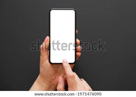 Woman using mobile phone with empty white screen on dark background