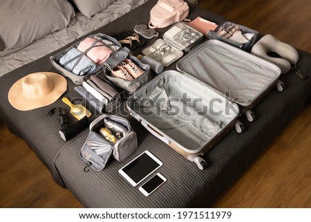 Organization of storage carrying necessary things in comfortable case with konmari method lying on bed. Empty open suitcase with neatly packing clothes, accessories, technique for travel trip vacation Royalty-Free Stock Photo #1971511979