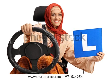 Young muslim woman in a car seat holding a learner plate isolated on white background