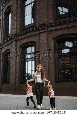 young beautiful mother with long hair with children on walk in street happiness joy fun motherhood