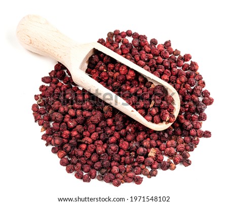 wood scoop on pile of dried magnolia berries (Schisandra Chinensis seeds) on white background