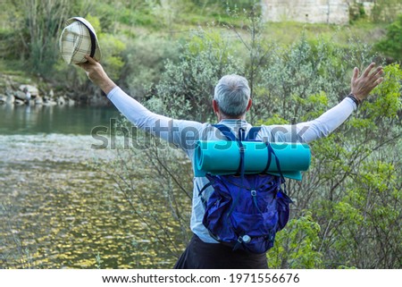 traveling man with backpack happily admiring the river