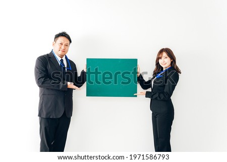 Two business people in suits holding a blackboard