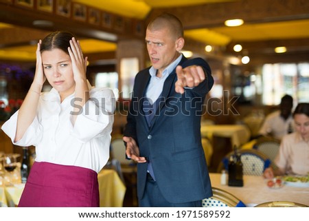 Angry man client of restaurant yelling at young waitress chasing her away Royalty-Free Stock Photo #1971589592